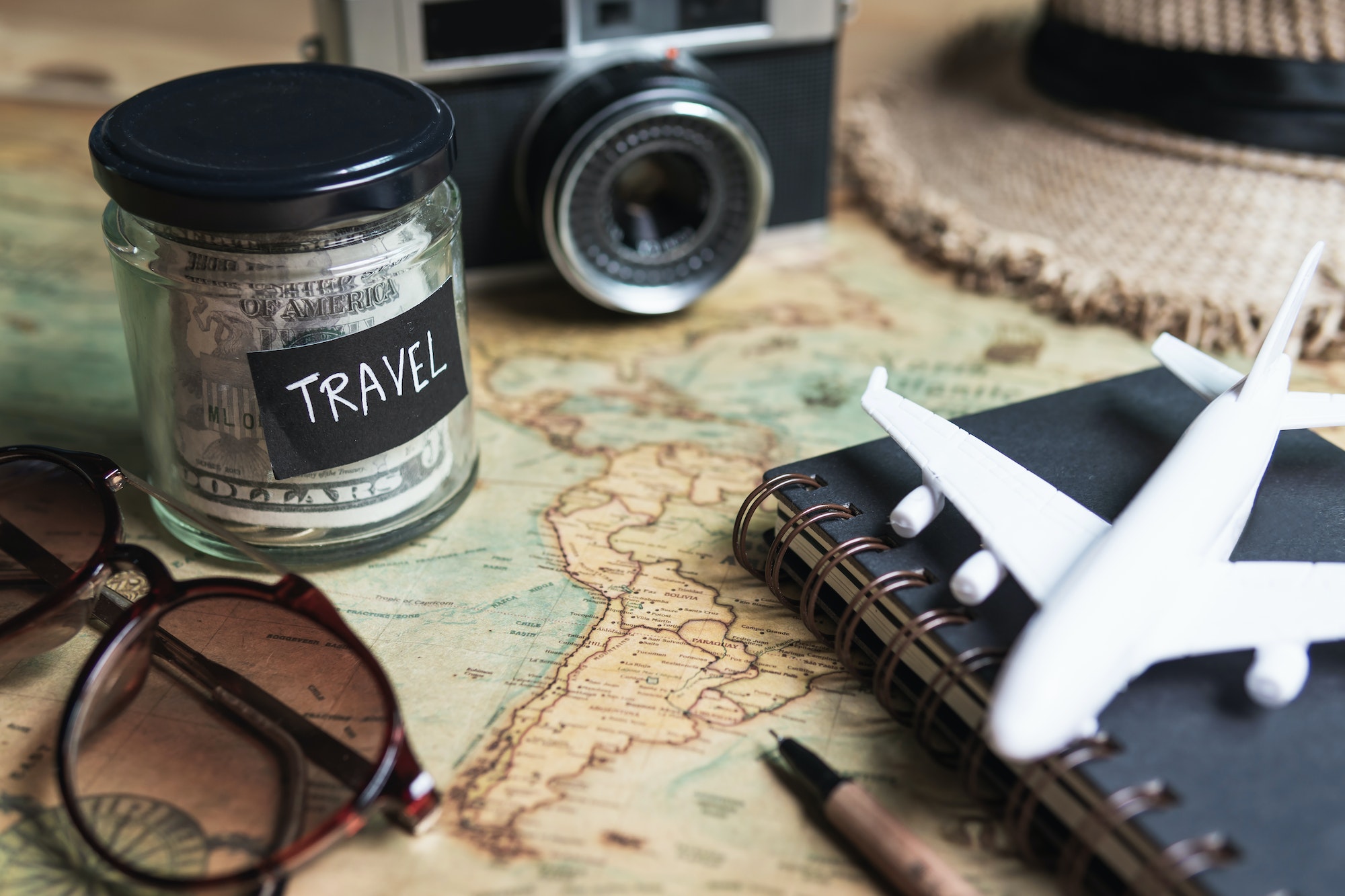 Vacation money saving in a glass with camera on map, Travel budget concept